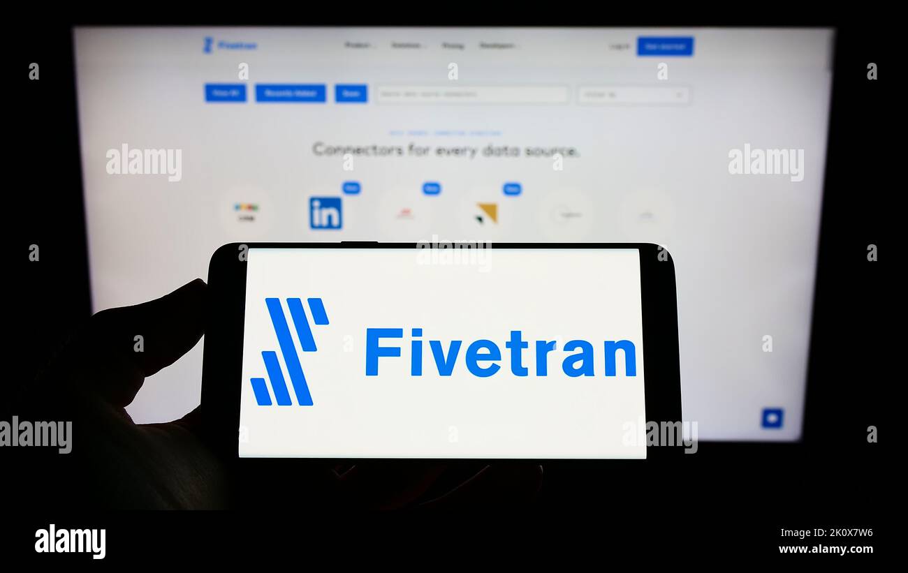 Person, die Mobiltelefon mit dem Logo des US-amerikanischen Datensoftwareunternehmens Fivetran Inc. Auf dem Bildschirm vor der Geschäftswebseite hält. Konzentrieren Sie sich auf die Telefonanzeige. Stockfoto