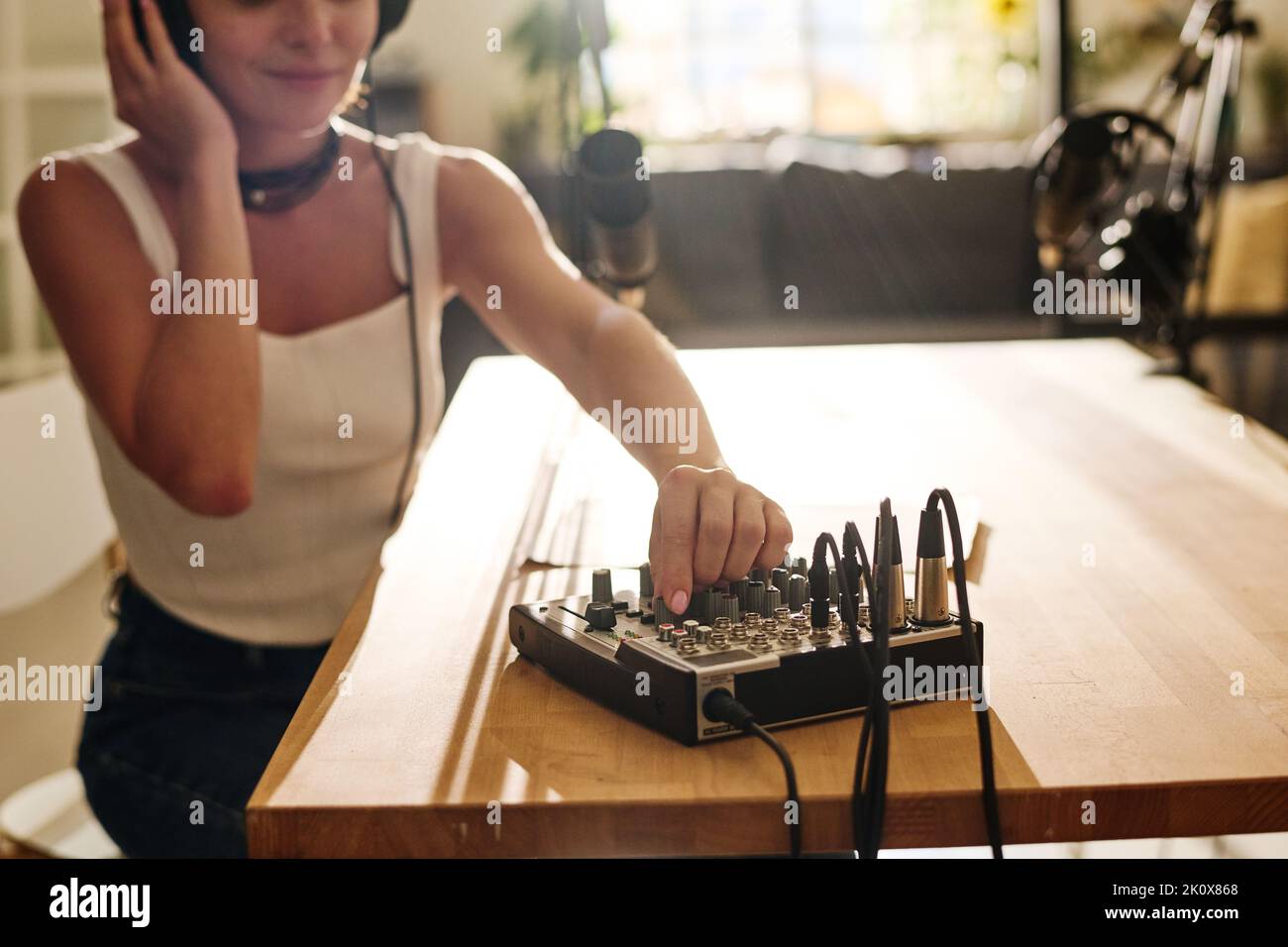 Hand einer jungen Frau rotierende Mischpult auf dem Soundboard am Arbeitsplatz, während die Lautstärke vor der Aufnahme Audio anpassen Stockfoto