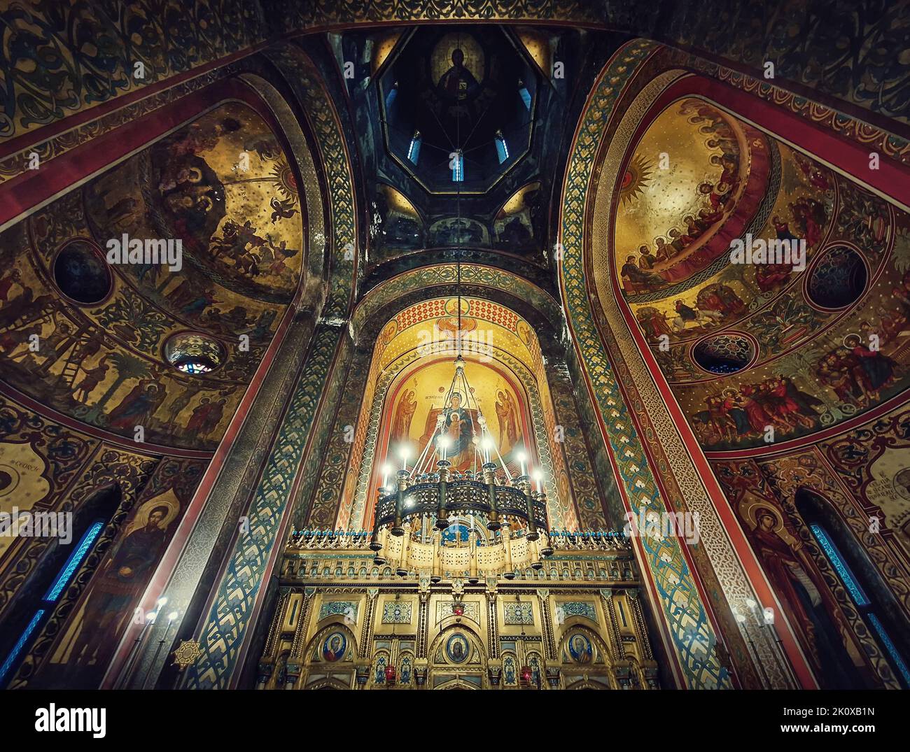 Architektonische Details im Inneren des Klosters Curtea de Arges. Der hohe Saal mit bemalten Ikonen, der goldene Altar und ein Leuchter mit Leuchtern Stockfoto