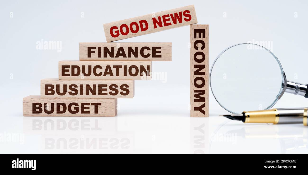 Business- und Economy-Konzept. Lupe, Stift und Holzblöcke mit dem Text - Handel & Unternehmen, Budget, Bildung, Wirtschaft, Finanzen und GOOD NEWS Stockfoto