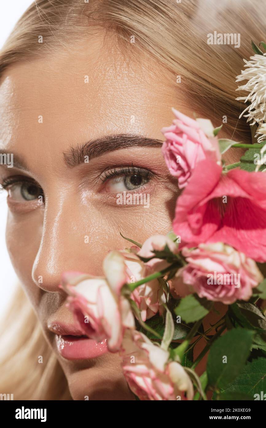 Schönheit Porträt von Charme junge blonde Frau mit Blume isoliert auf weißem Hintergrund. Kosmetik, natürliche Schönheit und ästhetische Kosmetologie Konzept. Stockfoto