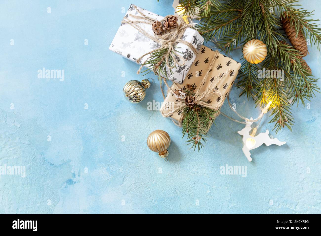 Weihnachtskugeln, Wintertanne mit Geschenkboxen und weihnachtsdekor auf blauem Steingrund. Weihnachts- und Neujahrskonzept. Blick von oben. Co Stockfoto