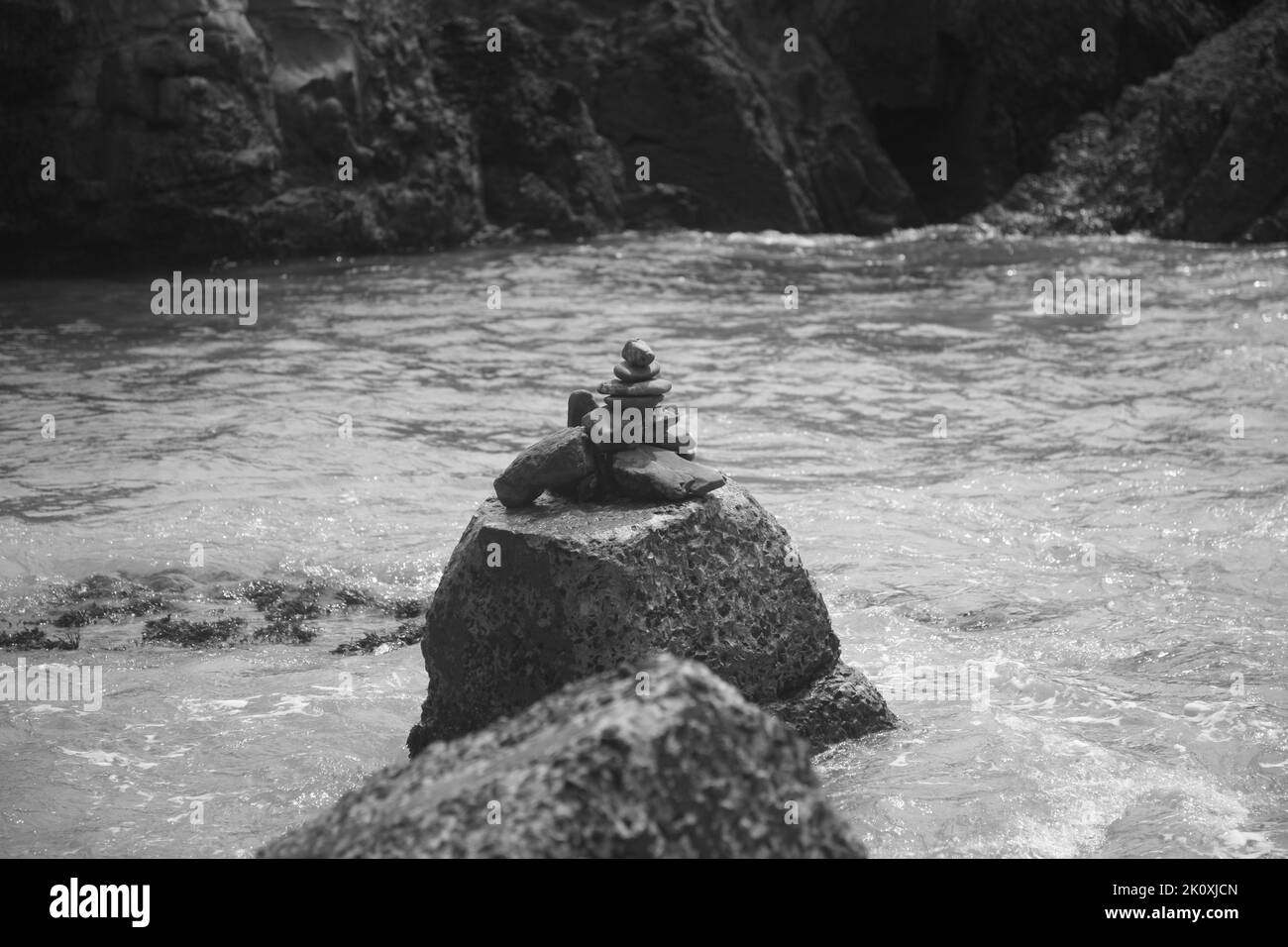 Eine Graustufenaufnahme von Felsen, die in einem See übereinander balanciert sind Stockfoto