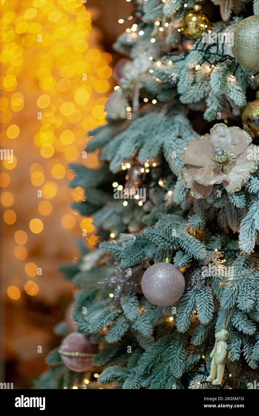 Nahaufnahme eines festlich geschmückten Weihnachtsbaums vor einem verschwommenen funkelnden Märchenhintergrund. Kopierbereich, vertikal. Entkochte Girlanden, Bokeh ef Stockfoto