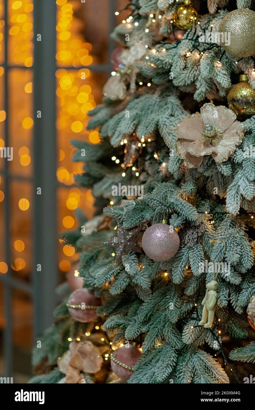 Nahaufnahme eines festlich geschmückten Weihnachtsbaums vor einem verschwommenen funkelnden Märchenhintergrund. Kopierbereich, vertikal. Entkochte Girlanden, Bokeh ef Stockfoto