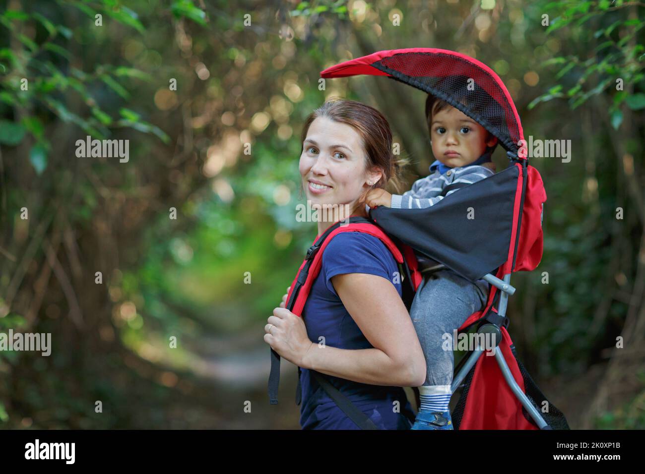 Mutter mit Kleinkind Kind im Rucksackträger wandert im Wald Stockfoto