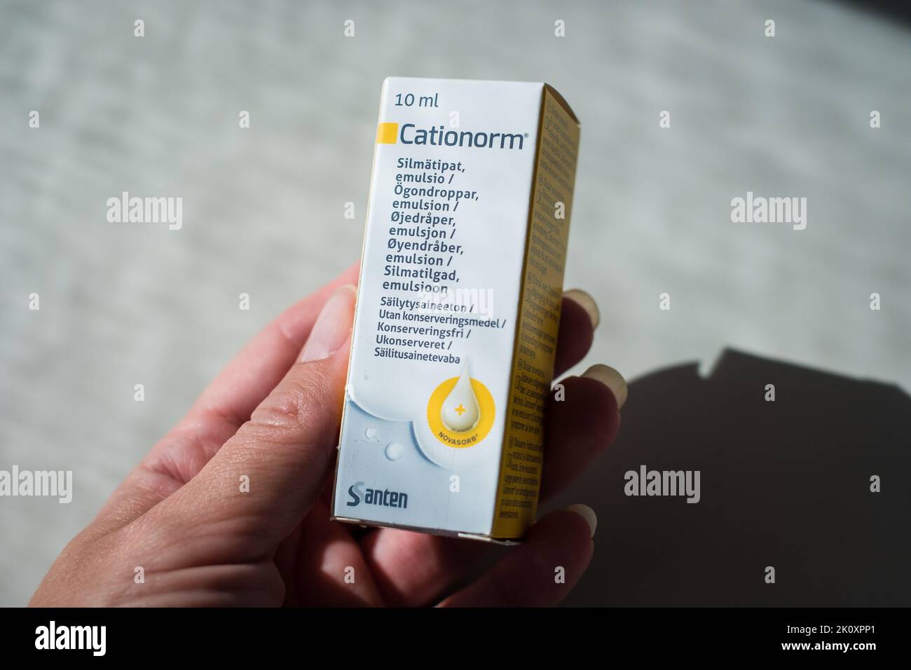 Hand hält Cationorm Eye Tropfen von Santen, um trockene, rote, juckende oder brennende Augen zu befeuchten und zu beruhigen. Trockensyndrom. Stockfoto