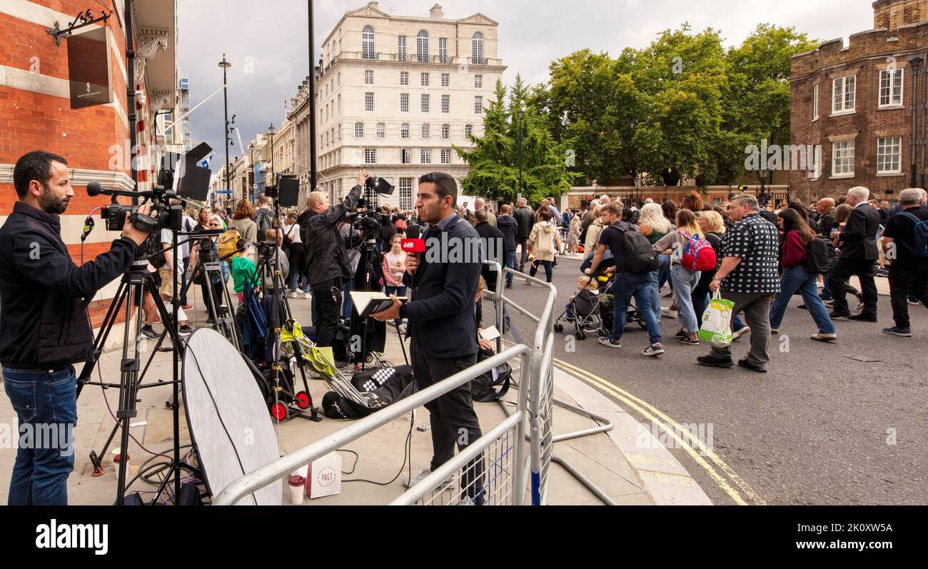 Ein Reporter und Kameramann in Presse und Menschenmengen, der über die Beerdigung von Königin Elizabeth II. Vor dem St. James Palace in London berichtete Stockfoto