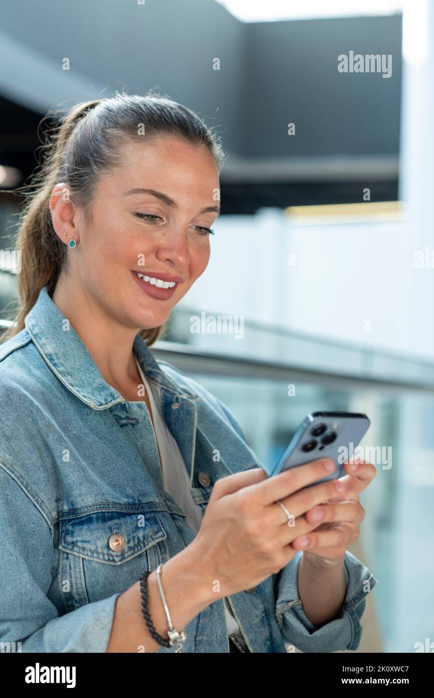 Junge Frau mit Mobiltelefon in einem modernen Büro - Stock Foto Stockfoto