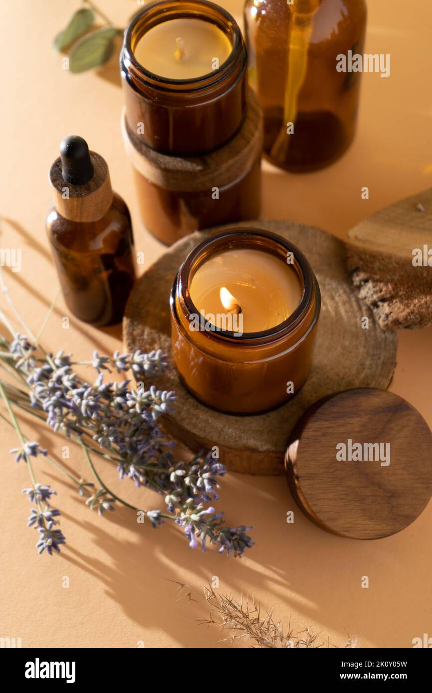 Sojalkerzen in einem Glas. Aromatherapie. Brennende Kerze und Lavendel. Deckel aus Holz für Gläser. Beigefarbener Hintergrund. Komfort und Entspannung. Handgefertigt. Inneneinrichtung. Stockfoto