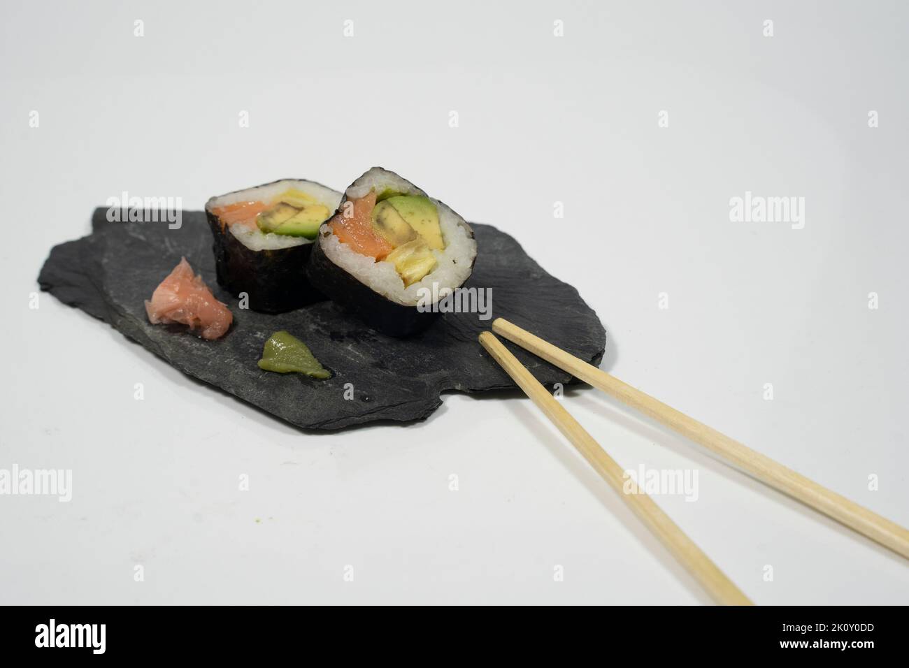 Zwei Sushi-Stücke auf einer Tafel mit Essstäbchen, Ingwer und Wasabi Stockfoto