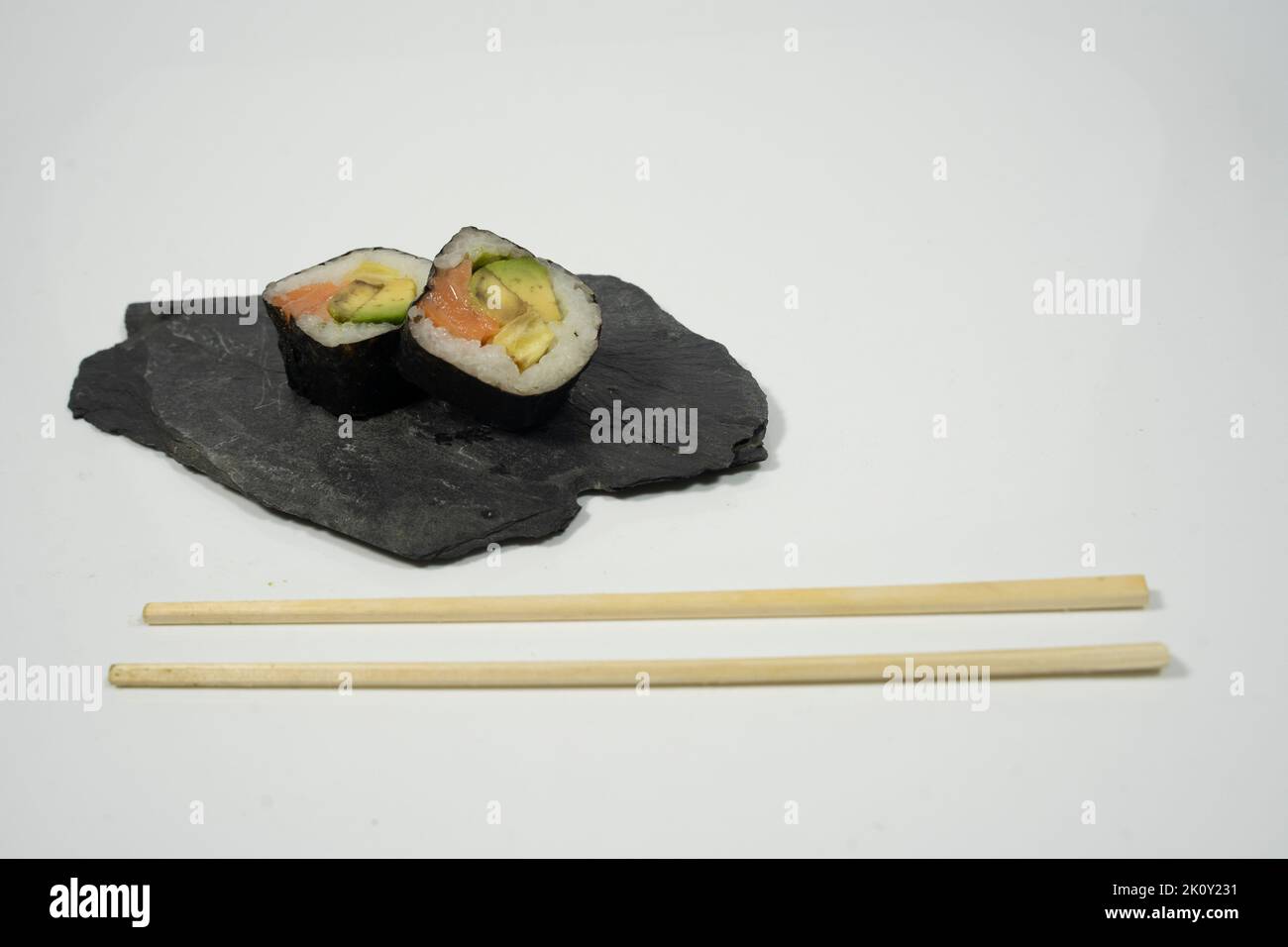 Zwei Sushi-Stücke auf einer Tafel mit Essstäbchen, Ingwer und Wasabi Stockfoto