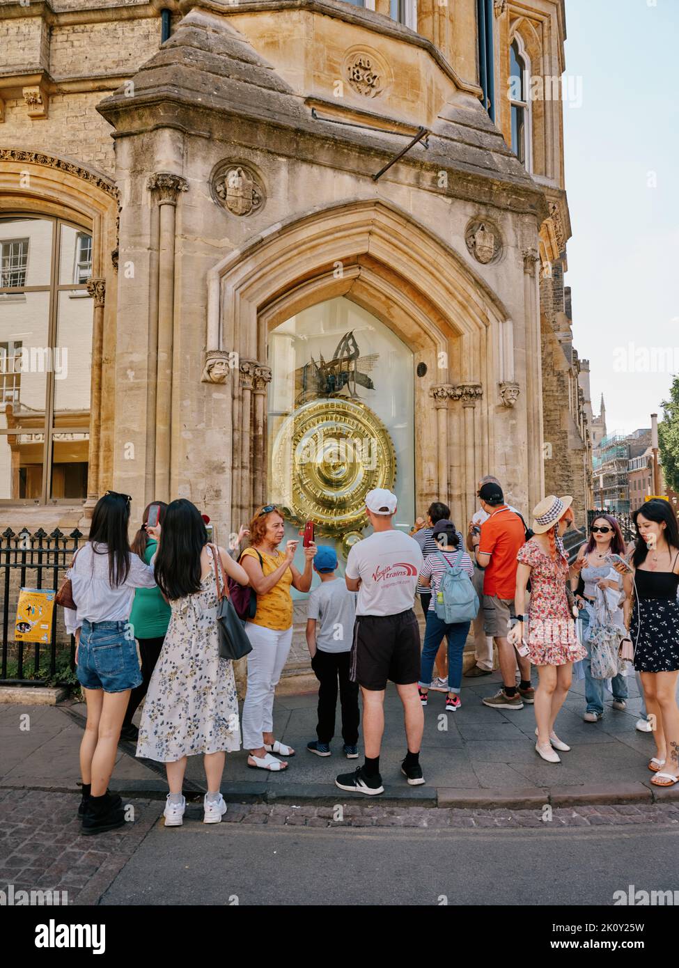 Die Corpus Clock / Grasshopper Clock und Sommertouristen vor der Taylor Library, Cambridge Cambridgeshire England - Tourismus Stockfoto