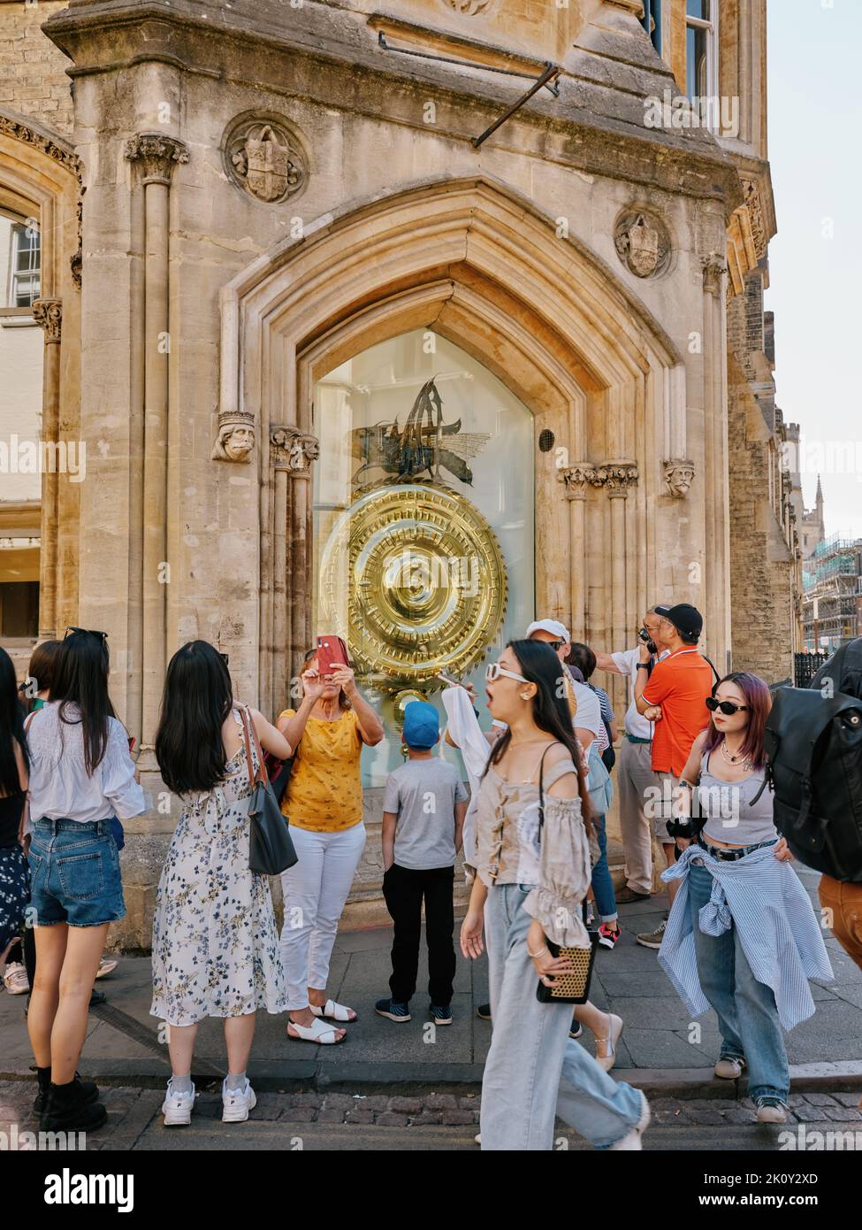 Die Corpus Clock / Grasshopper Clock und Sommertouristen vor der Taylor Library, Cambridge Cambridgeshire England - Tourismus Stockfoto