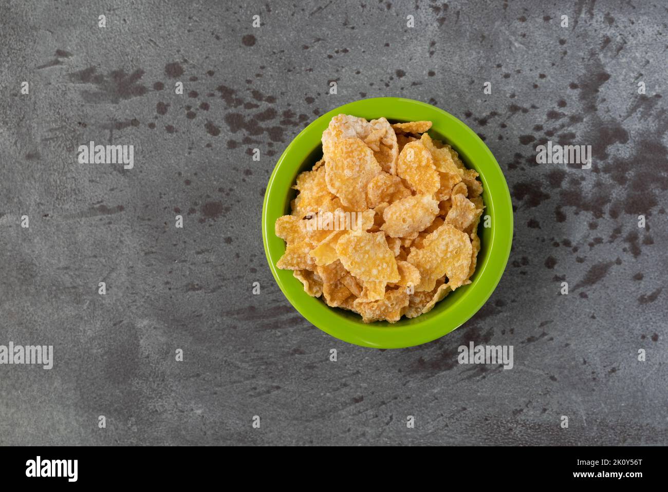 Draufsicht auf Milchkornflocken in einer grünen Schüssel auf grauem Hintergrund. Stockfoto