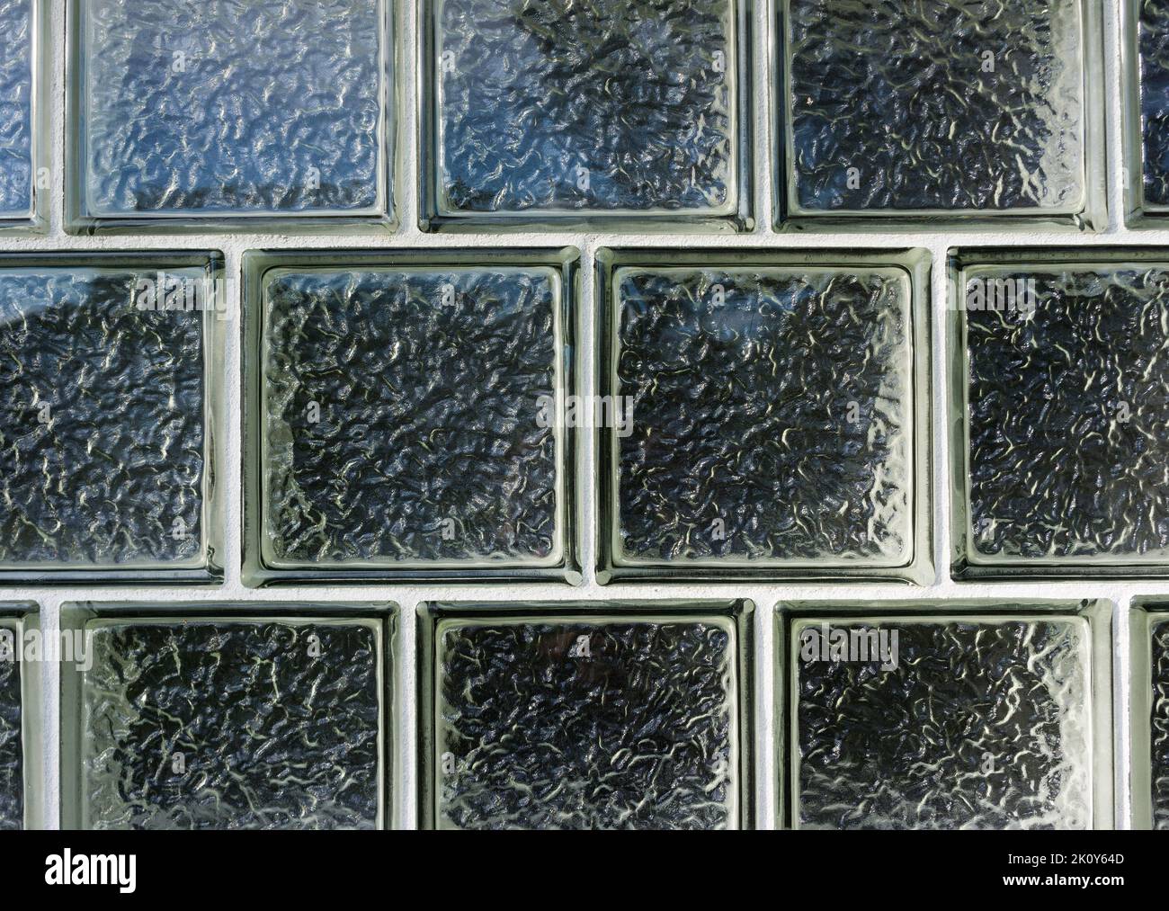 Mehrere Reihen von Glasblöcken, die für ein Fenster verwendet wurden, das Dichtungen und Undurchsichtigkeit im frühen Morgenlicht zeigt. Stockfoto Mehrere Reihen von Glasblöcken, die für ein Fenster verwendet wurden, das Dichtungen und Undurchsichtigkeit im frühen Morgenlicht zeigt. Stockfoto