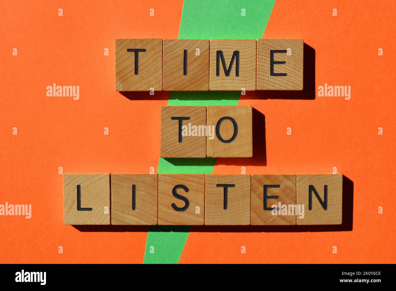 Zeit zum Zuhören, Wörter in Holzbuchstaben isoliert auf orangefarbenem und grünem Hintergrund Stockfoto