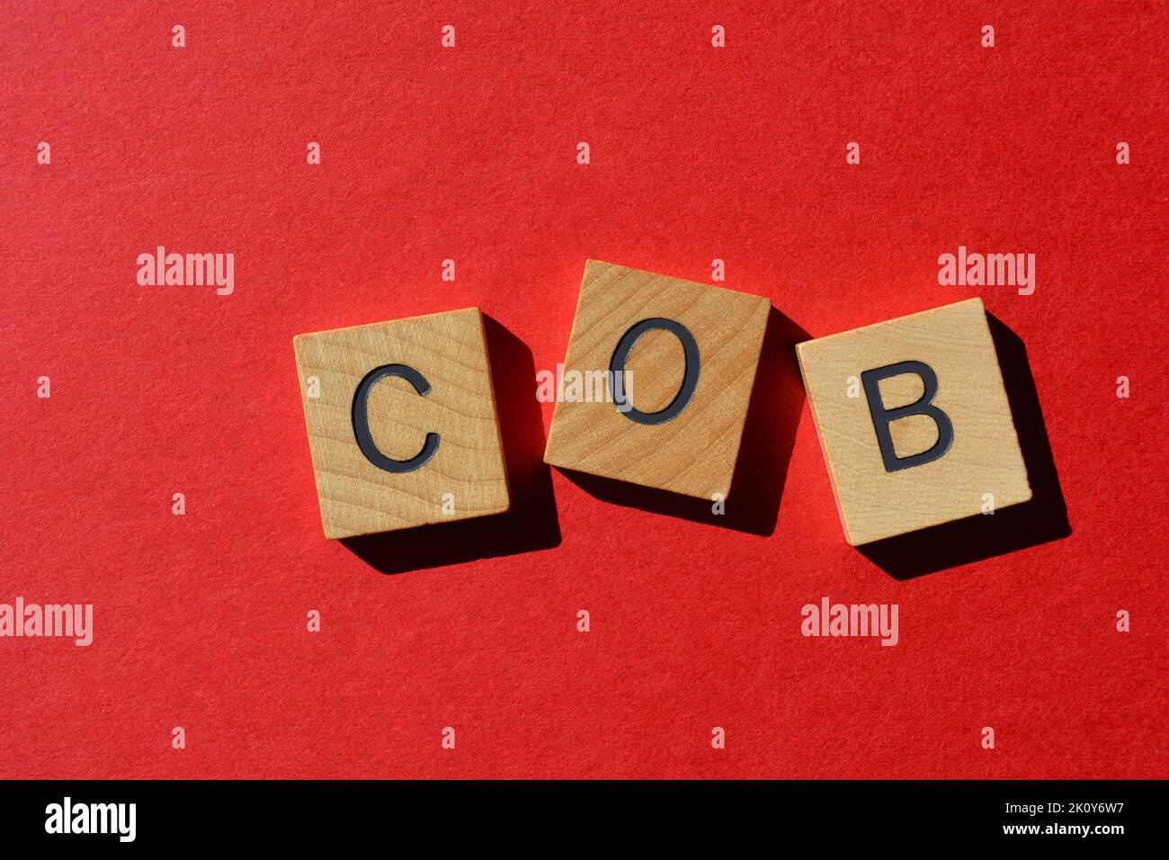 COB, Abkürzung für Close of Business in Holzbuchstaben isoliert auf rotem Hintergrund Stockfoto