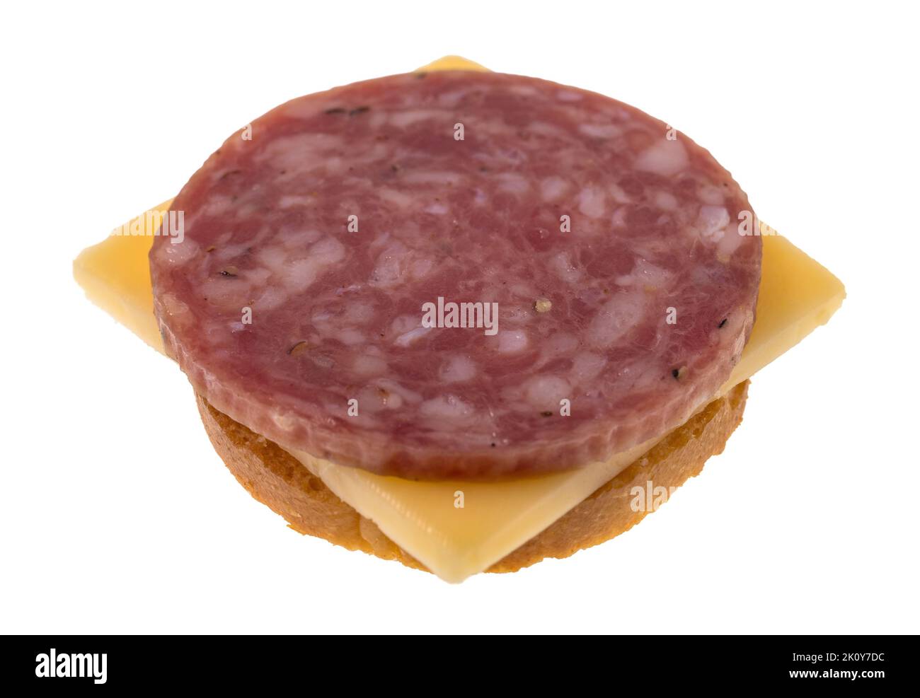 Seitenansicht einer Scheibe trockener Salami mit gouda-Käse auf einem runden Cracker, isoliert auf weißem Hintergrund. Stockfoto