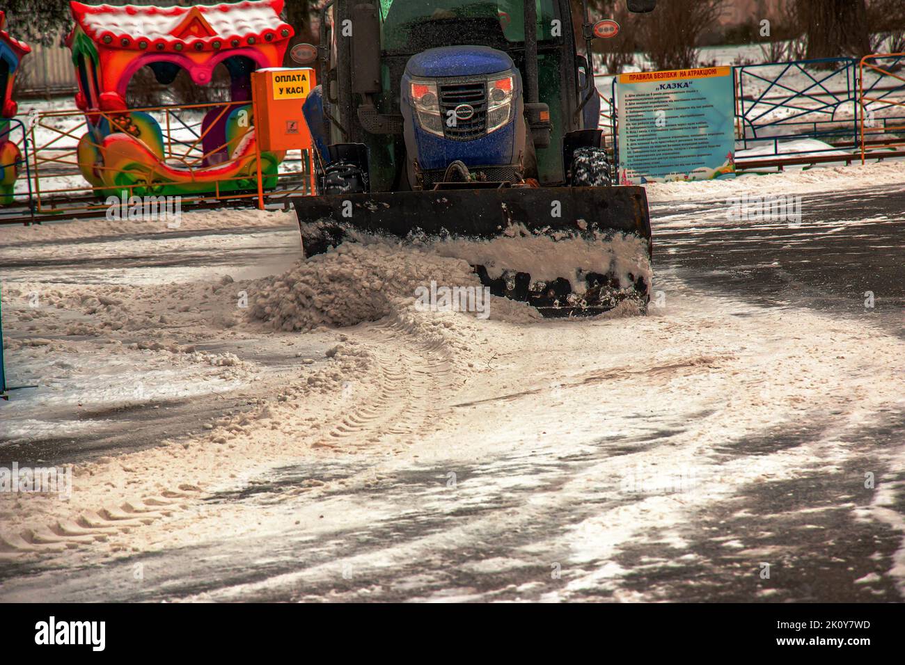 Dnipropetrovsk, Ukraine - 01.18.2022: Ein Arbeiter auf einem Traktor entfernt Schnee im Stadtpark. Stockfoto