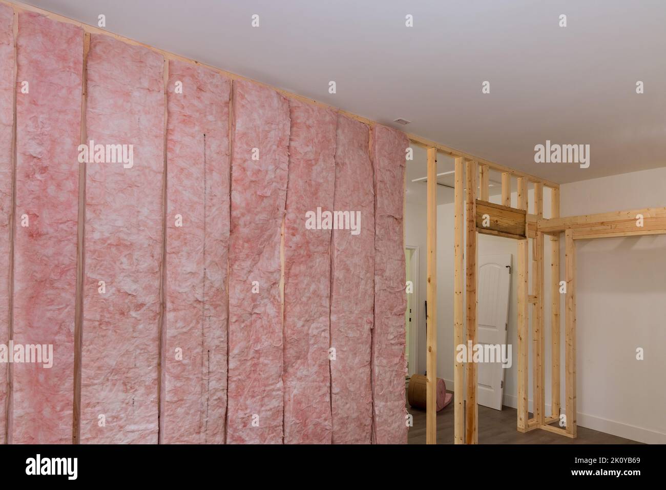 Die Installation von Mineralfaser-Glaswolle als Innen-Wärme- und Schalldämmung wird zwischen Balken durchgeführt, die die Wand einrahmen Stockfoto