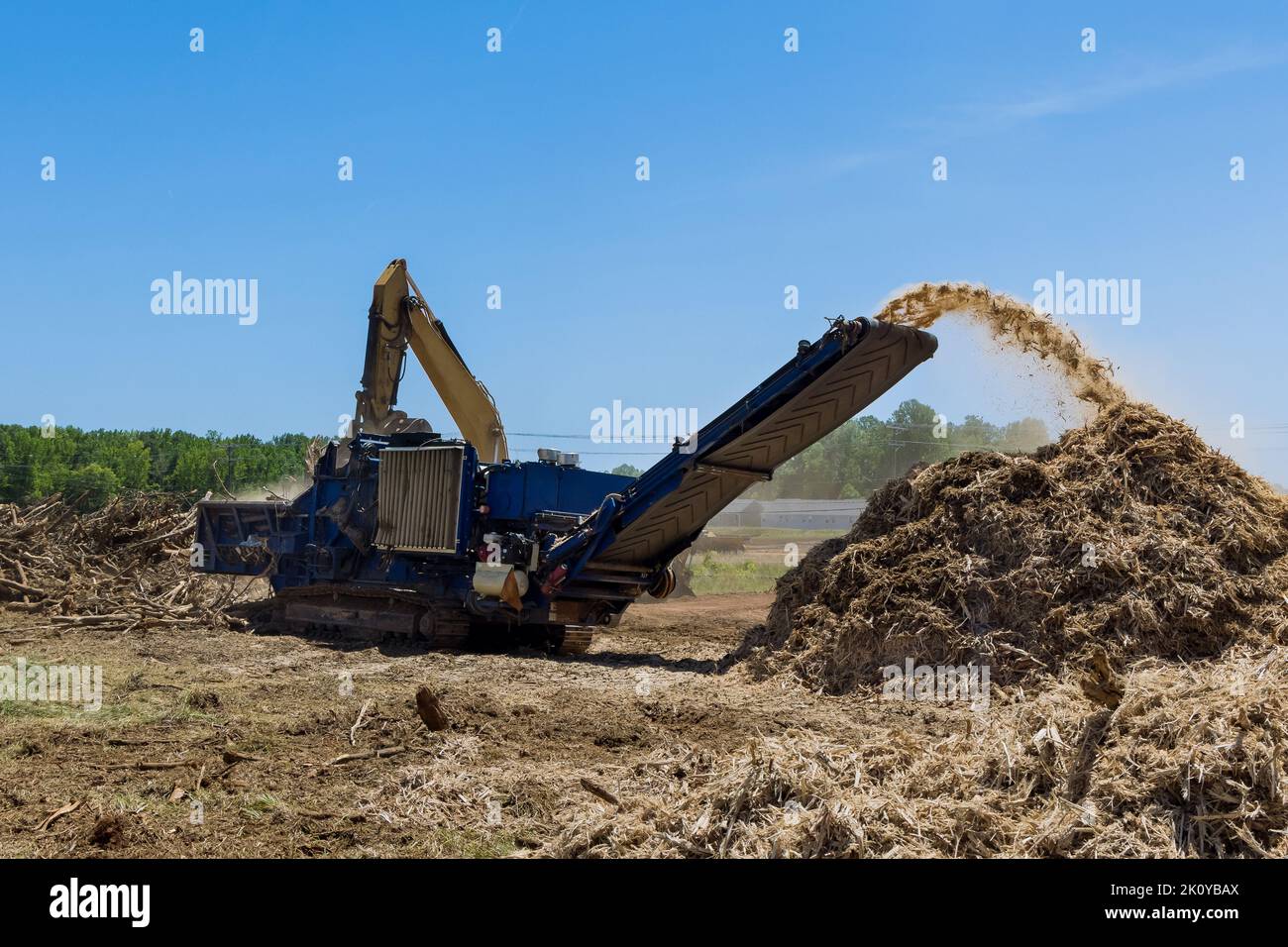 Das Land, auf dem eine Wohnsiedlung gebaut werden soll, hat Wurzeln, die von einer industriellen Schreddermaschine in Chips geschreddert werden Stockfoto