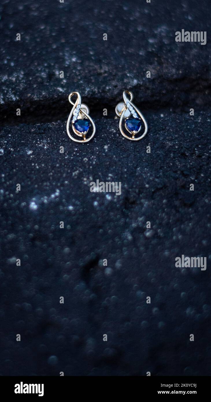 Ein selektives, fokussiertes Bild eines Paares goldener Diamanten und Saphirohrringe auf schwarzem Hintergrund Stockfoto