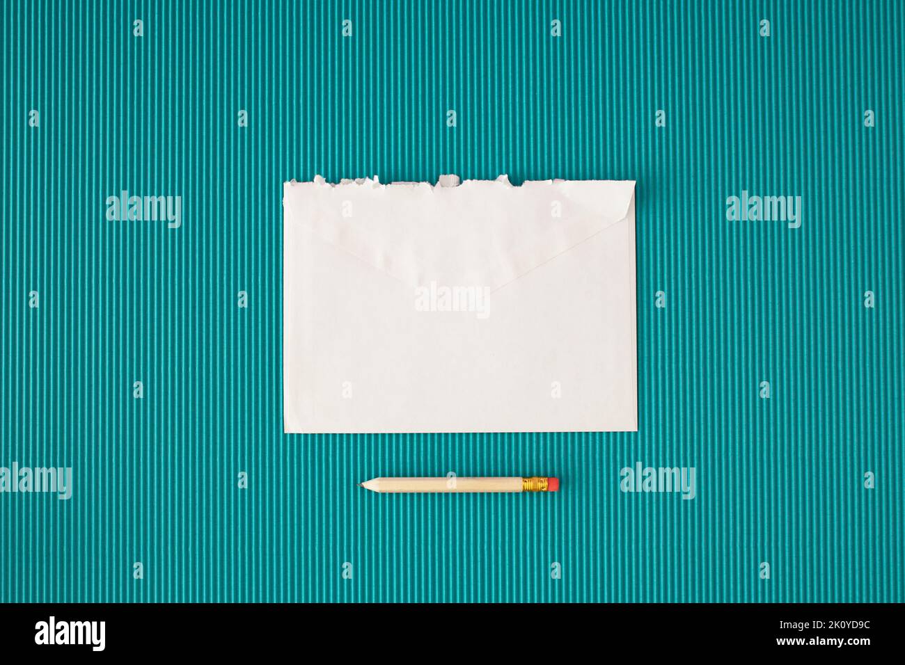Weißer zerrissener Umschlag und Bleistift auf blauem Hintergrund. Minimales Konzept mit Kopierplatz. Stockfoto