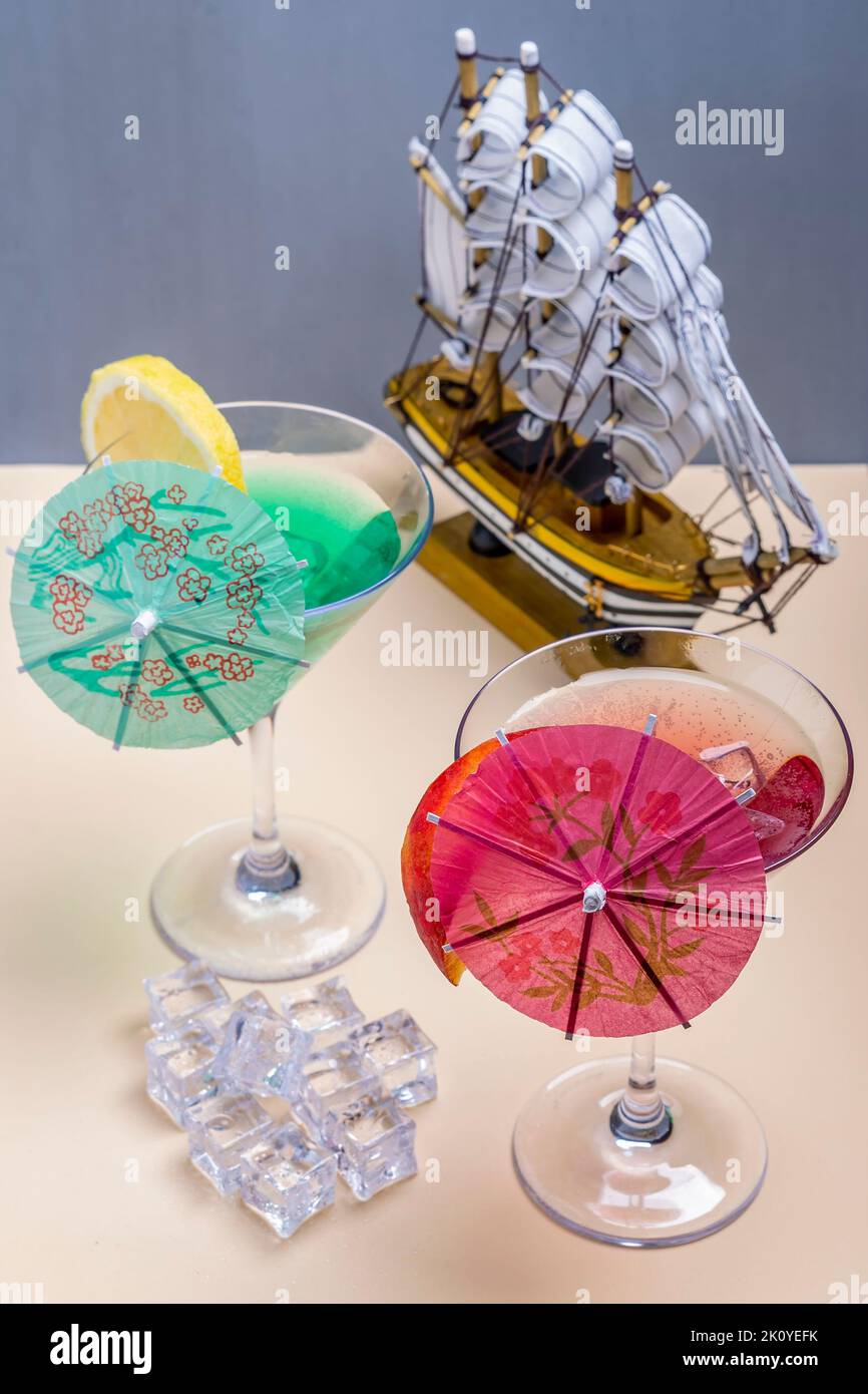 Zwei Gläser mit bunten Cocktails und ein Modellschiff im Hintergrund Stockfoto