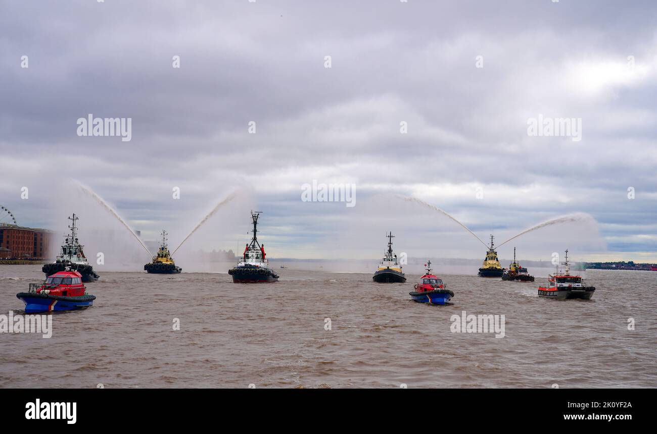 Flussschlepper führen Fleur De Lis vor, als sich Schiffe auf dem River Mersey in Liverpool vor den Three Graces (Liver Building, Cunard Building und Port of Liverpool Building) für eine maritime Hommage an Königin Elizabeth II. Versammeln. Die vor ihrer Beerdigung am Montag in der Westminster Hall in London im Staat liegen wird. Bilddatum: Mittwoch, 14. September 2022. Stockfoto