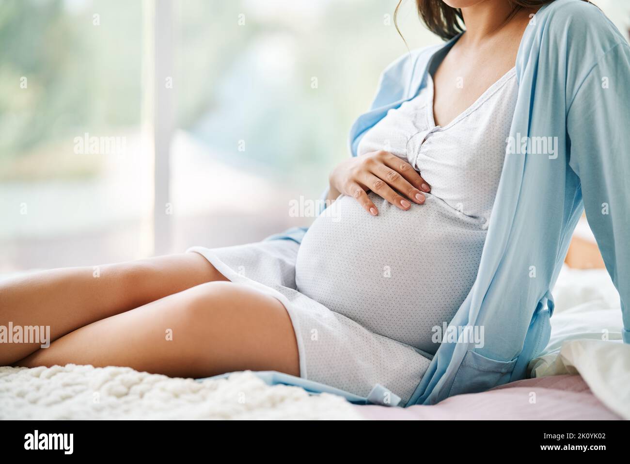 Nahaufnahme einer Schwangeren, die ihren Bauch hält. Babyerwartung, Mutterschaftspflege, Schwangerschaft und Sicherheitskonzept Stockfoto