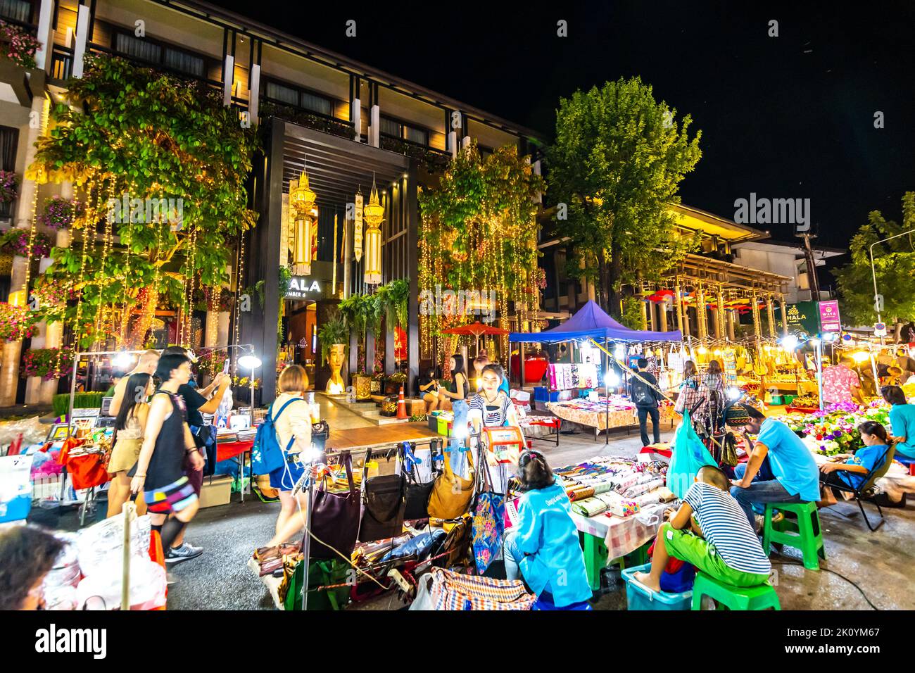CHIANG MAI, THAILAND - 3.11.2019: Nachtmarkt in der Stadt Chiang Mai kurz nach Sonnenuntergang. Touristen gehen auf der Straße. Thailändische Verkäufer im Stall Stockfoto