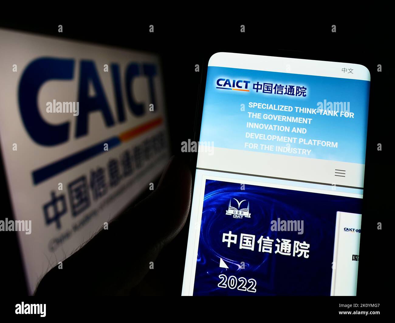 Person mit Mobiltelefon und Webseite des chinesischen Kommunikationsforschungsinstituts CAICT auf dem Bildschirm mit Logo. Konzentrieren Sie sich auf die Mitte des Telefondisplays. Stockfoto