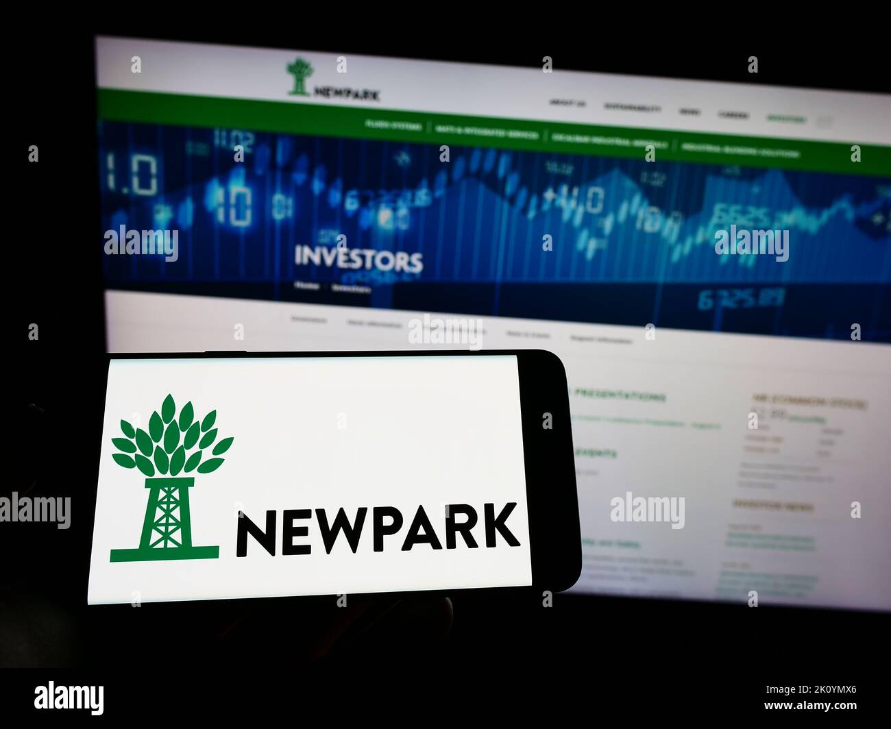 Person mit Mobiltelefon und Logo des Bohrsystemunternehmens Newpark Resources Inc. Auf dem Bildschirm vor der Webseite. Konzentrieren Sie sich auf die Telefonanzeige. Stockfoto
