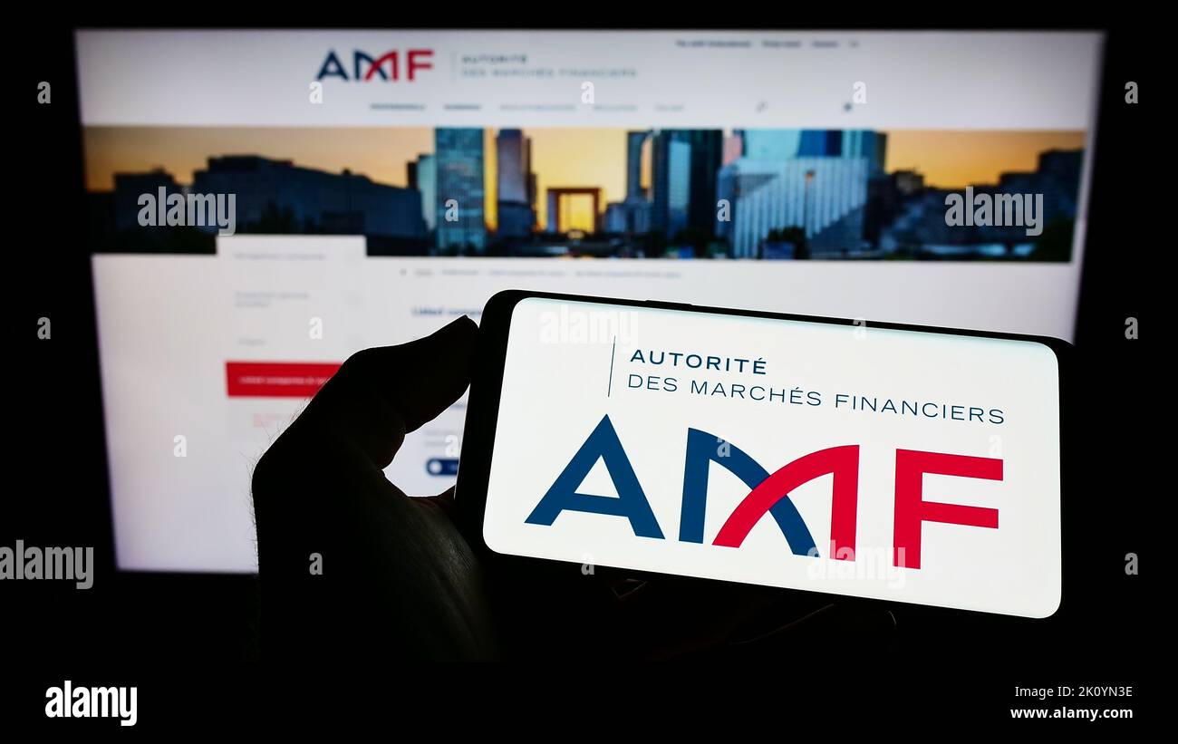 Person mit Mobiltelefon und Logo der französischen Regulierungsbehörde Autorite des Marken Financiers (AMF) auf dem Bildschirm vor der Webseite. Konzentrieren Sie sich auf die Telefonanzeige. Stockfoto Person mit Mobiltelefon und Logo der französischen Regulierungsbehörde Autorite des Marken Financiers (AMF) auf dem Bildschirm vor der Webseite. Konzentrieren Sie sich auf die Telefonanzeige. Stockfoto