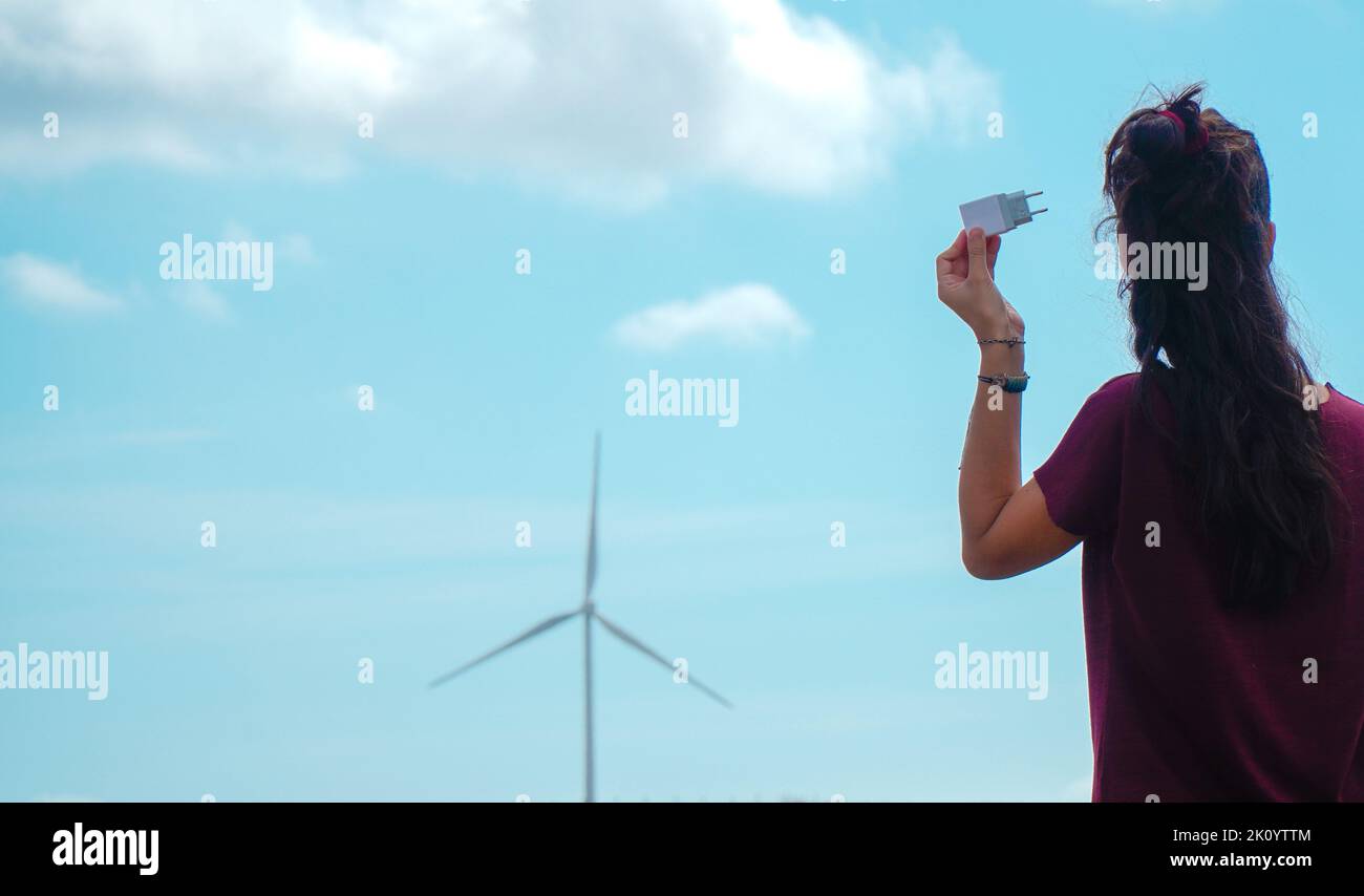 Ein Stecker neben einem Windkraftwerk mit Kopierplatz. Grüne Energie. Erneuerbare Energien Stockfoto Ein Stecker neben einem Windkraftwerk mit Kopierplatz. Grüne Energie. Erneuerbare Energien Stockfoto