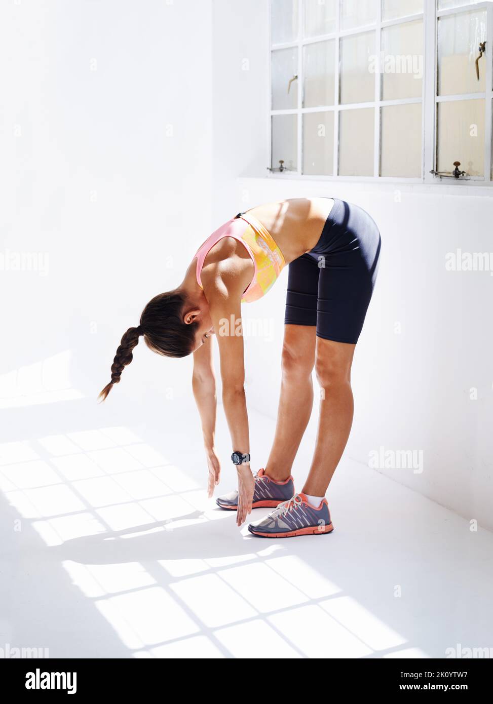 Eine attraktive junge Frau berührt beim Training ihre Zehen. Stockfoto