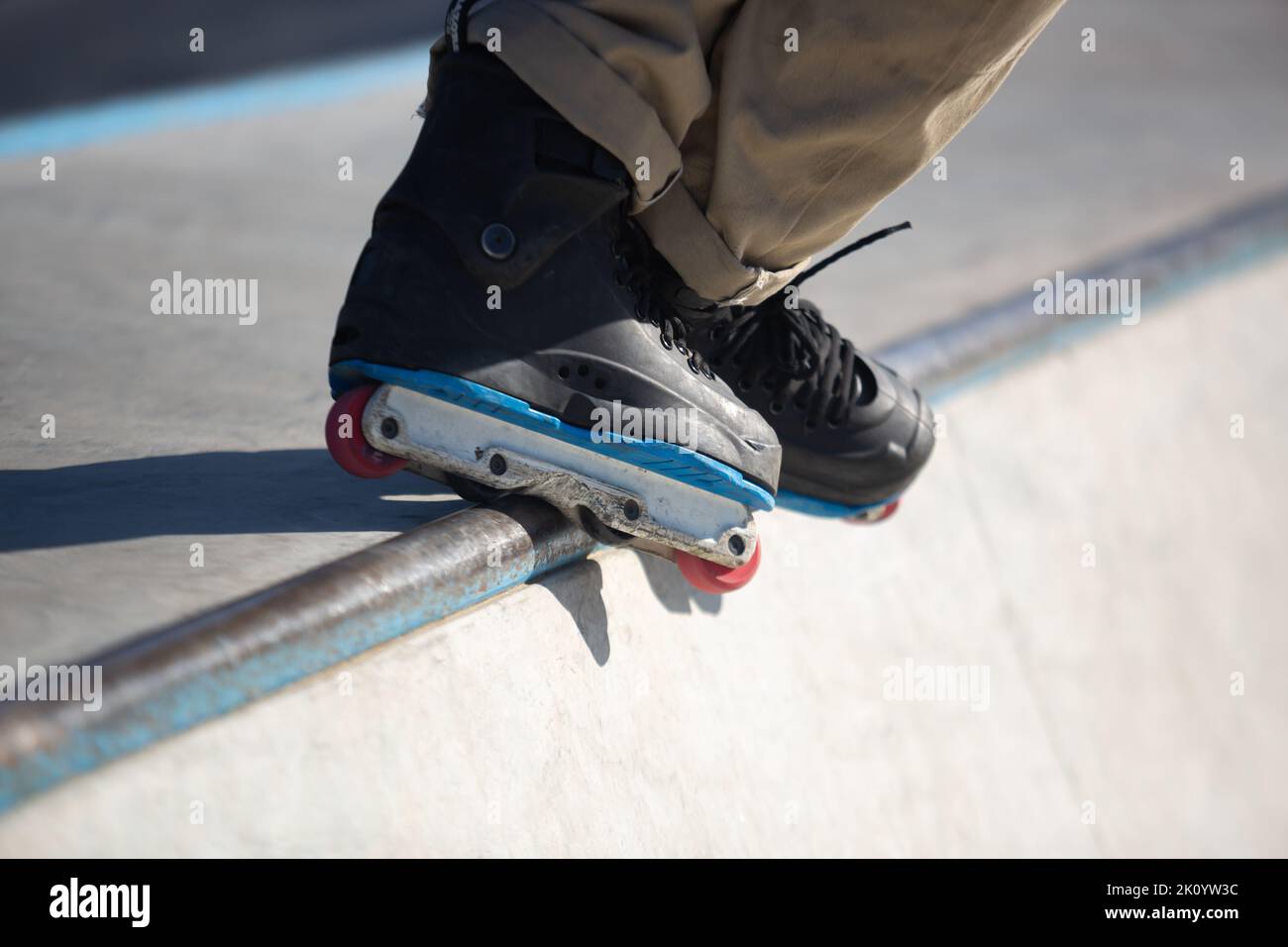 Roller Blader Schleifen auf Schiene im Skatepark. Inline-Skater führt bs Unity Grind Trick in Mini-Rampe im Freien Stockfoto