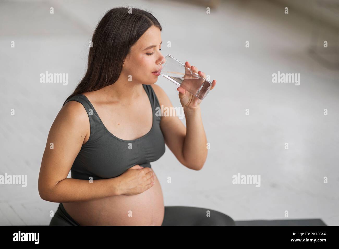 Körperhydratisierung. Schöne Junge Schwanger Frau Trinkwasser Aus Glas Zu Hause Stockfoto