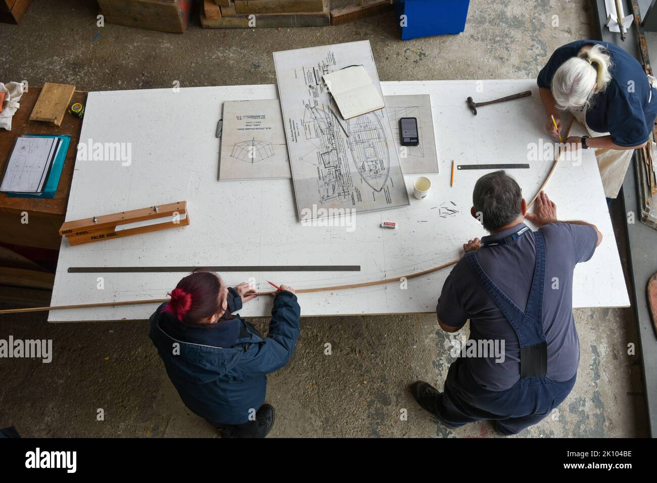 Schiffbau und Reparaturen im Boathouse Nummer 4, Portsmouth historische Schiffswerft. Mitarbeiter arbeiten an Plänen auf einem Holztisch. Stockfoto