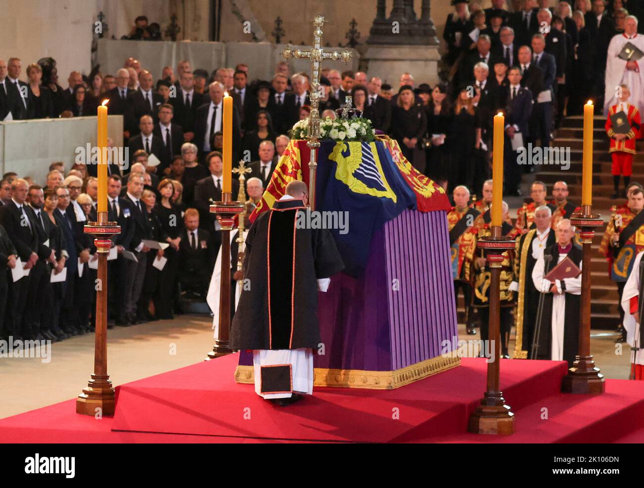 Ein Priester hält ein Kreuz neben dem Sarg von Königin Elizabeth II., das im Royal Standard mit der Imperial State Crown auf der Oberseite drapiert ist, während es auf der Katafalque in Westminster Hall, London, ruht, wo es vor ihrer Beerdigung am Montag in einem Zustand liegen wird. Bilddatum: Mittwoch, 14. September 2022. Stockfoto