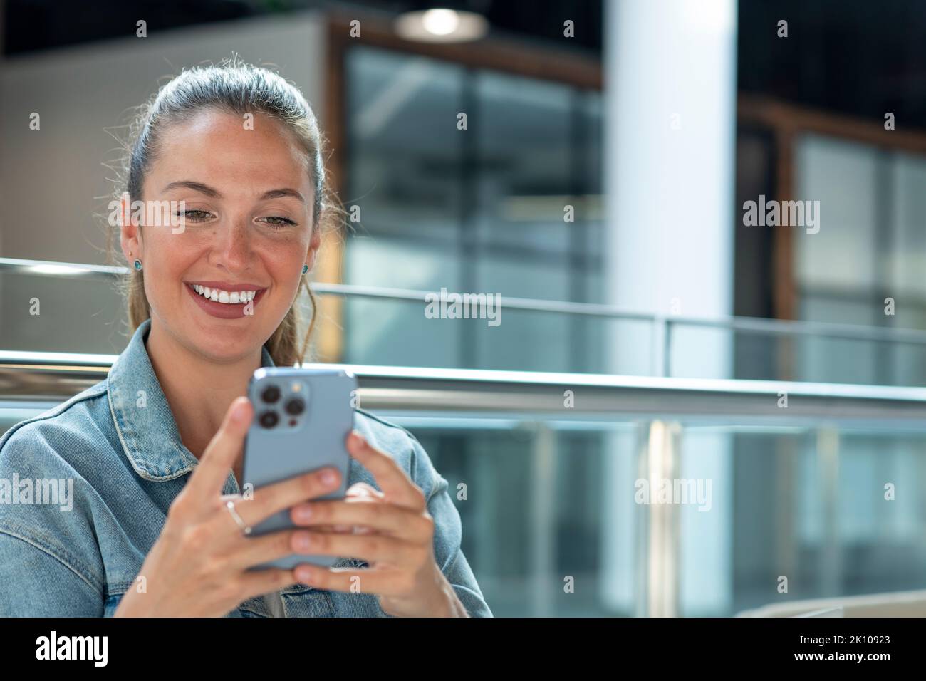 Junge Frau mit Mobiltelefon in einem modernen Büro - Stock Foto Stockfoto