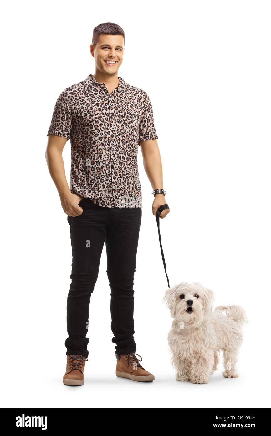 In voller Länge Porträt eines jungen Mannes in einem Hemd mit Tierdruck, der mit einem maltesischen Pudelhund auf einem Blei auf weißem Hintergrund posiert Stockfoto