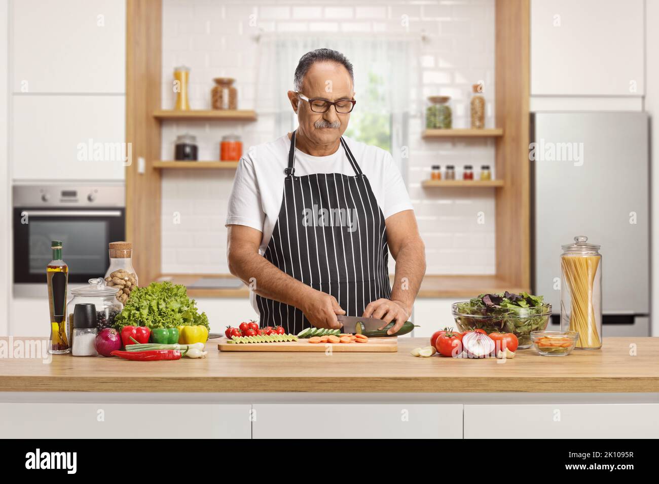 Reifer Mann, der Gemüse schneidet und einen Salat in der Küche zubereitet Stockfoto