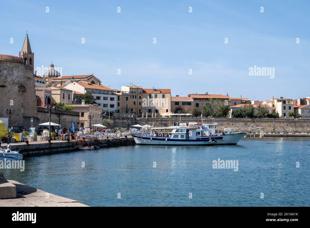 Blick auf die Altstadt Zitadelle und den Hafen vom Hafen von Alghero, Sardinien, Italien mit Neptuns Grotto-Kreuzfahrtbooten. Stockfoto