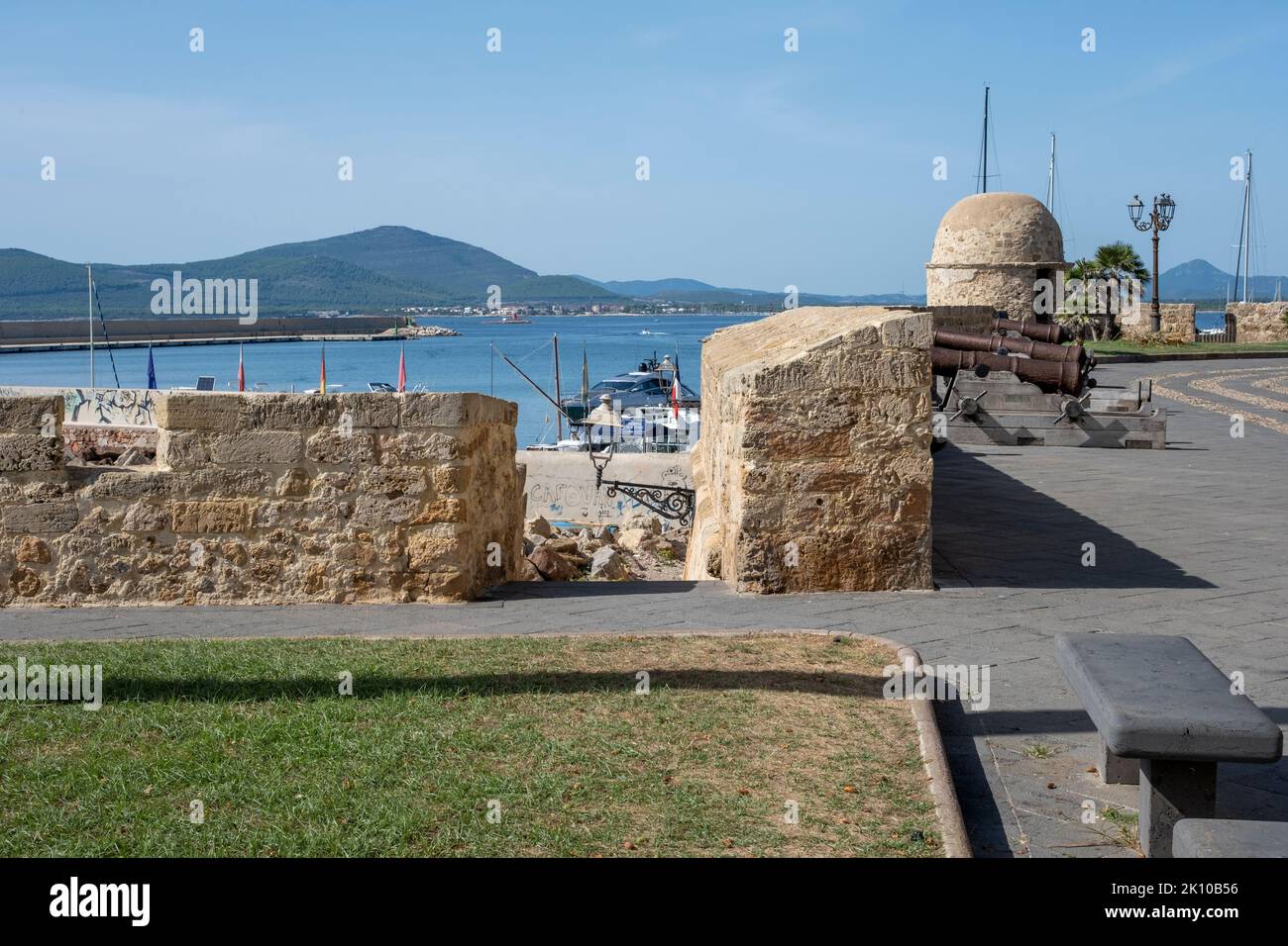 Alte Kanonen auf den Wällen der Altstadt von Alghero, Sardinien, Italien, mit Blick auf die Klippen und das Vorgebirge von Capo Caccia Stockfoto