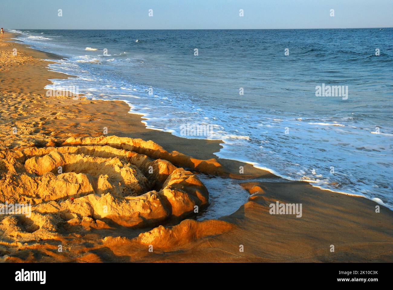 Wellen nähern sich einer kreisförmigen Sandskulptur am Ufer des Georgica Beach East Hampton Long Island Stockfoto