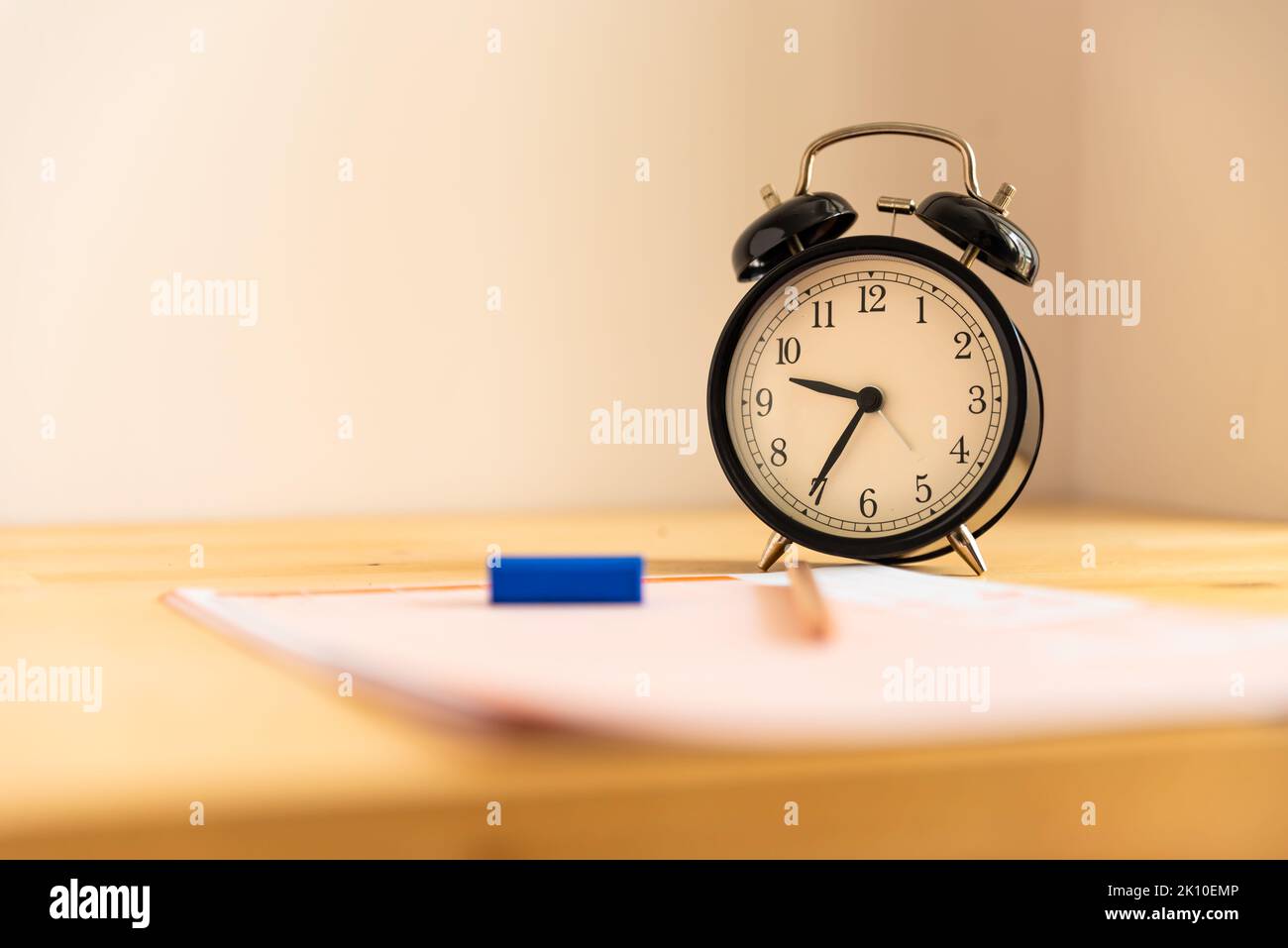Prüfung im Bildungskonzept, Bleistift, Radiergummi und Wecker auf Holztisch, Stockfoto