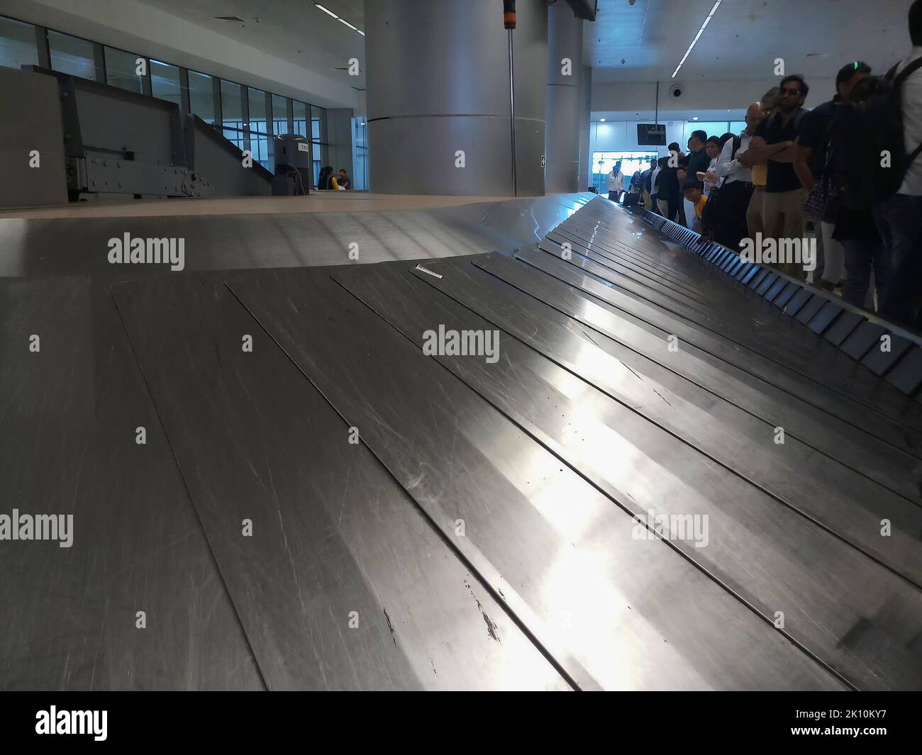 Delhi , Indien - 14.. Mai 2019 : Nahaufnahme des automatisierten Gepäckgürtels am Flughafen in Bewegung warten Passagiere neben dem leeren Gürtel auf ihr Gepäck Stockfoto