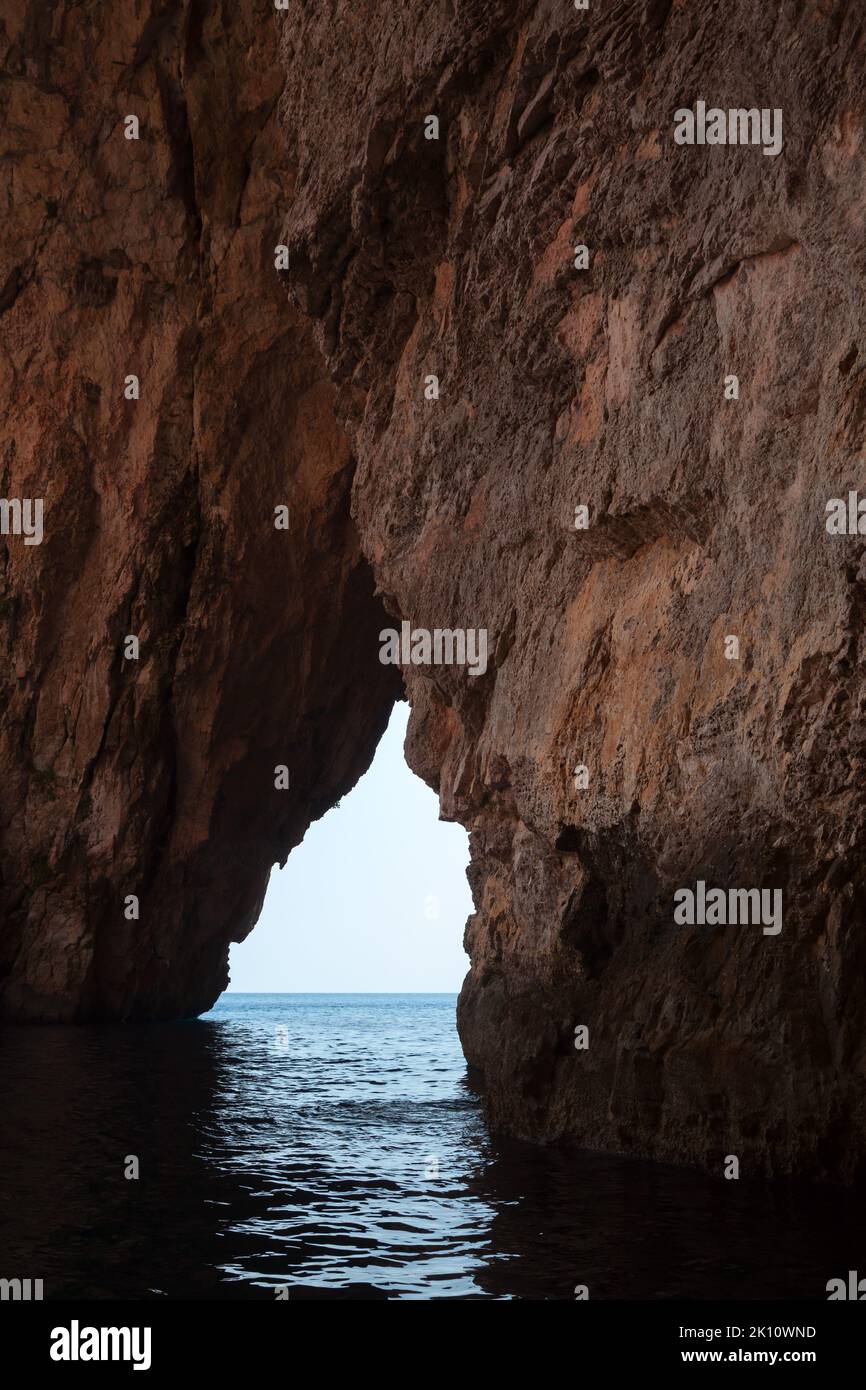 Dunkle Landschaft, leere Höhle in Küstenfelsen. Blaue Grotte, Malta. Vertikales Foto Stockfoto